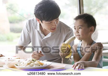 Stock Image - Man talking with little boy and having food together, Family, Leisure Activities. Fotosearch