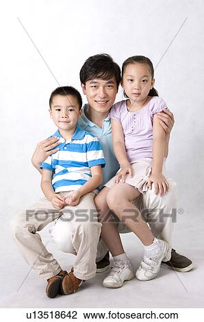 Stock Image - Two children sitting on man's legs and looking at the camera, Family, Leisure Activities. Fotosearch