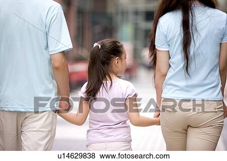 Stock Photo - Young family with little girl holding hands together of rear view, Family, Leisure Activities. Fotosearch