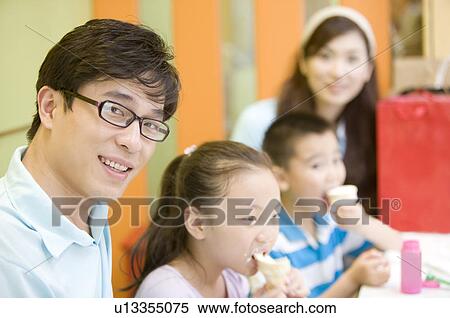 Young family with two children eating ice cream and looking at the camera, Family, Leisure Activities View Large Photo Image Stock Photography - Young family with two children eating ice cream and looking at the camera, Family, Leisure Activities. Fotosearch