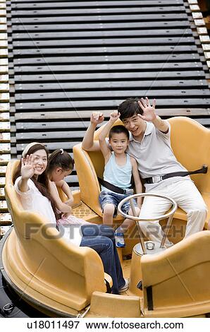 Stock Photo - Young family with two children playing in the amusement park and gesturing with smile, Family, Leisure Activities. Fotosearch