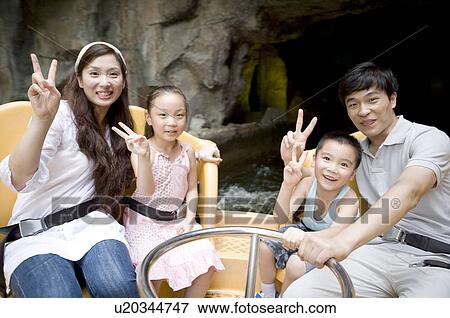 Stock Photo - Young family with two children playing in the amusement park and gesturing with smile, Family, Leisure Activities. Fotosearch