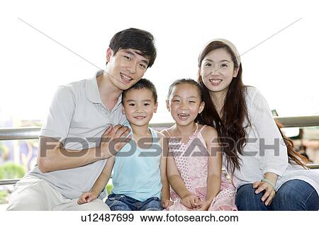 Young family with two children sitting and smiling at the camera together, Family, Leisure Activities View Large Photo Image Stock Photo - Young family with two children sitting and smiling at the camera together, Family, Leisure Activities. Fotosearch