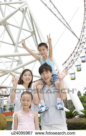 Stock Photo - Young family with two children standing near ferries wheel and gesturing with smile, Family, Leisure Activities. Fotosearch