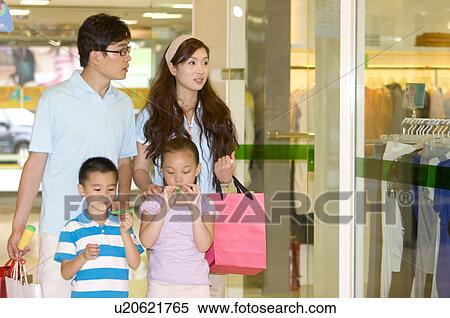 Stock Photography - Young family with two children walking in the shopping mall and holding shopping bags,, Family, Leisure Activities. Fotosearch