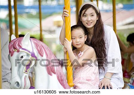 Young woman and little girl sitting on the carrousel and looking away, Family, Leisure Activities View Large Photo Image Stock Photography - Young woman and little girl sitting on the carrousel and looking away, Family, Leisure Activities. Fotosearch