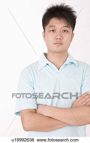 Stock Photo - Portrait of man standing with arms crossed, Men, Facial Expression. Fotosearch