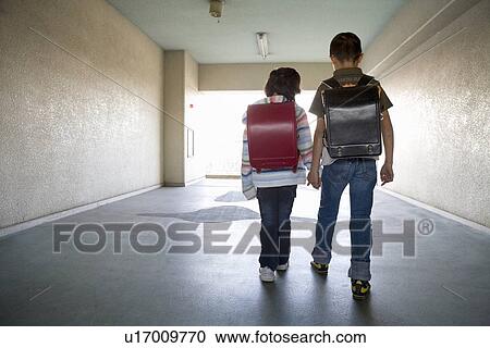 Stock Image - Boy and girl walking hallway. Fotosearch