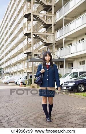 Stock Photo - Teenage girl walking in front of apartment building. Fotosearch