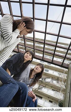 Stock Image - Three women chatting at park. Fotosearch