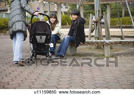 Stock Image - Three women chatting at square. Fotosearch