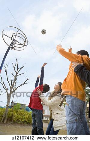 Stock Image - Two boys throwing ball with mothers. Fotosearch