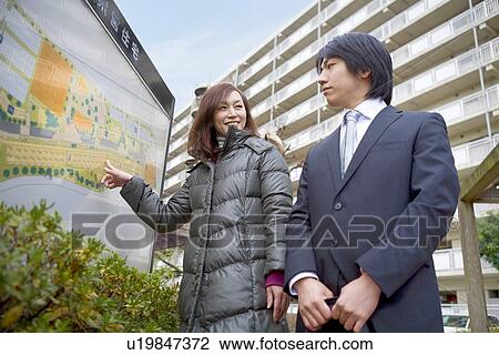 Stock Image - Woman showing guideboard to young man. Fotosearch