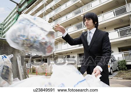 Stock Image - Young man throwing a garbage bag to drop off site. Fotosearch