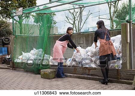 Stock Image - Young women greeting each other at drop off site. Fotosearch