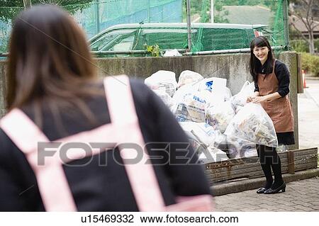 Stock Image - Young women greeting each other at drop off site. Fotosearch