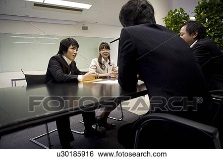 Four people meeting at table View Large Photo Image Stock Photograph - Four people meeting at table. Fotosearch