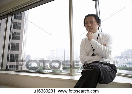 Stock Image - Mature man sitting by the window. Fotosearch