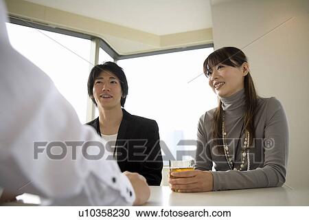 Stock Image - Three people meeting at table. Fotosearch