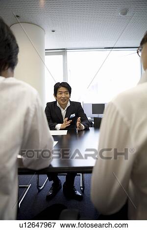 Three people meeting at table View Large Photo Image Stock Photo - Three people meeting at table. Fotosearch