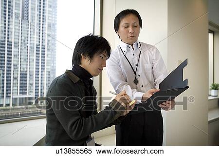 Two people checking document by the window View Large Photo Image Stock Photography - Two people checking document by the window. Fotosearch