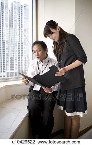 Two people checking file by the window View Large Photo Image Stock Image - Two people checking file by the window. Fotosearch
