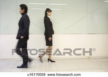 Stock Photo - Two people walking in office. Fotosearch