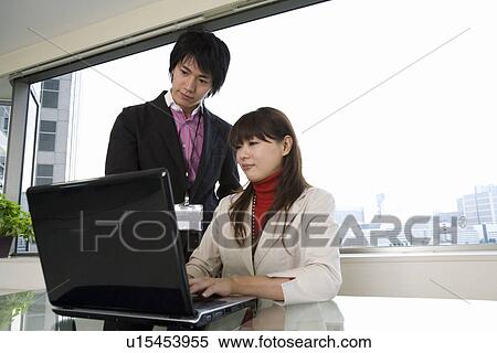 Stock Photography - Young man and woman looking at computer. Fotosearch