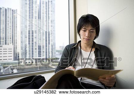 Stock Image - Young man looking documents. Fotosearch