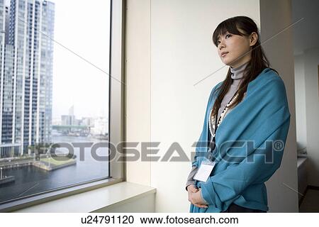 Young woman standing by the window View Large Photo Image Stock Image - Young woman standing by the window. Fotosearch