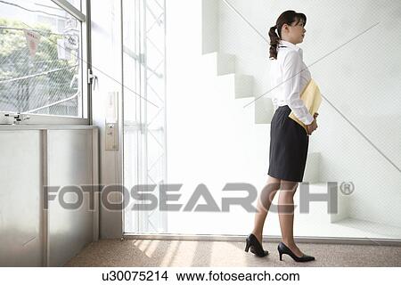 Picture - Young woman walking in office. Fotosearch