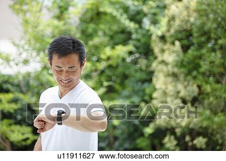 Stock Photo - Mature man looking wristwatch. Fotosearch