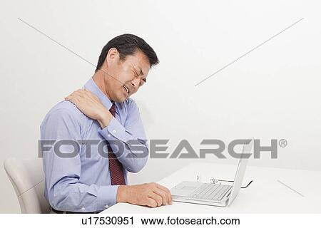 Stock Image - Mature man suffering from pain on shoulder. Fotosearch