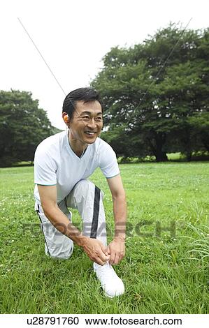 Stock Image - Mature man tying shoelaces. Fotosearch