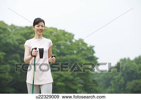 Stock Photo - Mature woman enjoying Nordic walking. Fotosearch