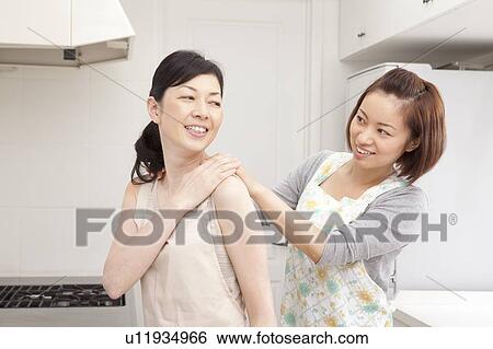 Stock Photograph - Young woman massaging mature woman's shoulder. Fotosearch