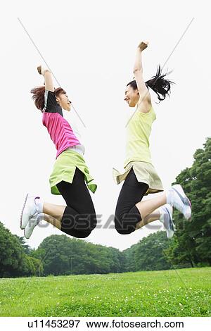 Stock Photo - Mid adult woman and young woman jumping. Fotosearch