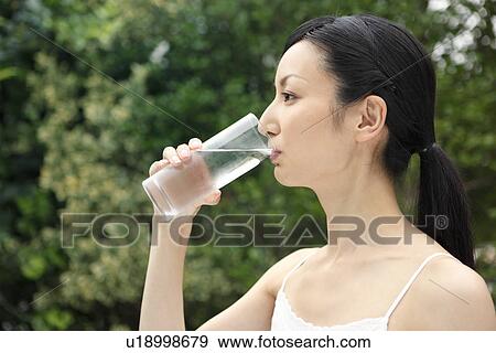 Mid adult woman drinking water View Large Photo Image Stock Photo - Mid adult woman drinking water. Fotosearch