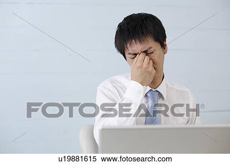 Stock Photography - Young businessman getting eyestrain. Fotosearch