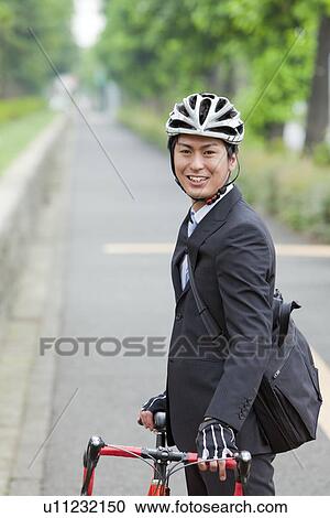 Stock Image - Young businessman holding bicycle. Fotosearch