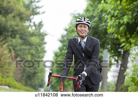 Stock Photo - Young businessman holding bicycle. Fotosearch