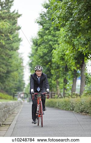 Picture - Young businessman riding bicycle. Fotosearch