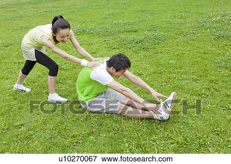 Stock Photo - Young man and mid adult woman stretching. Fotosearch