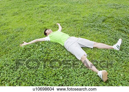 Picture - Young man lying on grass. Fotosearch