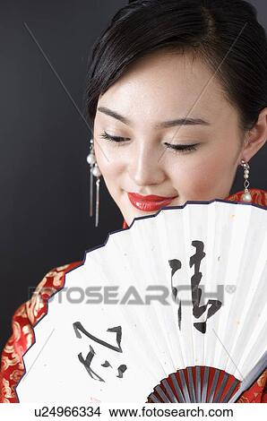 Picture - Close up of young woman holding a folding fan. Fotosearch