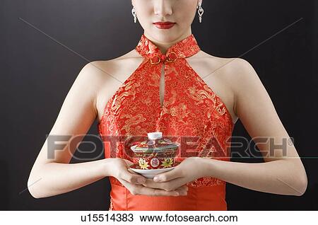 Close up of young woman in cheongsam holding a cup of tea View Large Photo Image Stock Image - Close up of young woman in cheongsam holding a cup of tea. Fotosearch