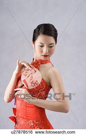 Portrait of a young woman holding a fan View Large Photo Image Stock Photograph - Portrait of a young woman holding a fan. Fotosearch
