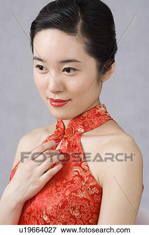 Stock Photo - Young woman in cheongsam, hand on chest. Fotosearch