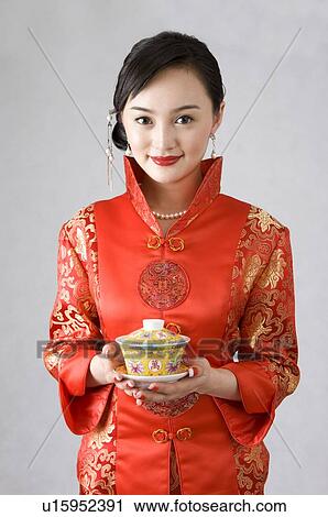 Young woman in cheongsam holding a cup of tea View Large Photo Image Stock Image - Young woman in cheongsam holding a cup of tea. Fotosearch