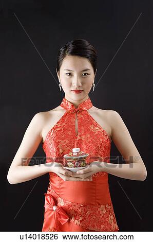 Young woman in cheongsam holding a cup of tea View Large Photo Image Stock Photograph - Young woman in cheongsam holding a cup of tea. Fotosearch